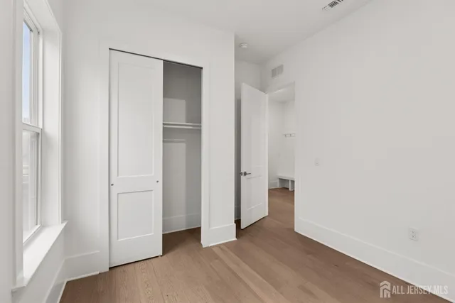 a view of an empty room with closet and wooden floor