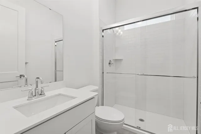 a bathroom with a shower sink vanity mirror and toilet