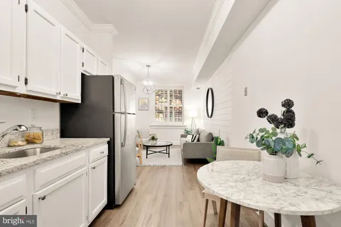 a kitchen with stainless steel appliances kitchen island granite countertop a refrigerator a stove a sink dishwasher and white cabinets with wooden floor