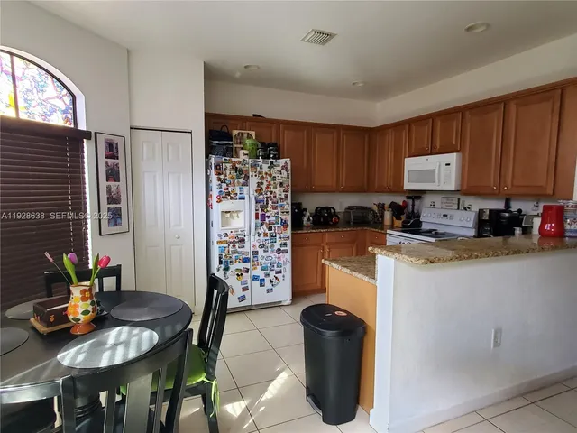 a kitchen with stainless steel appliances granite countertop a refrigerator a stove a sink dishwasher with a dining table and chairs