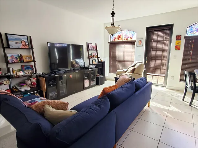 a living room with furniture a flat screen tv and a large window
