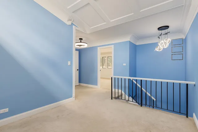 a view of a hallway with wooden floor and chandelier fan