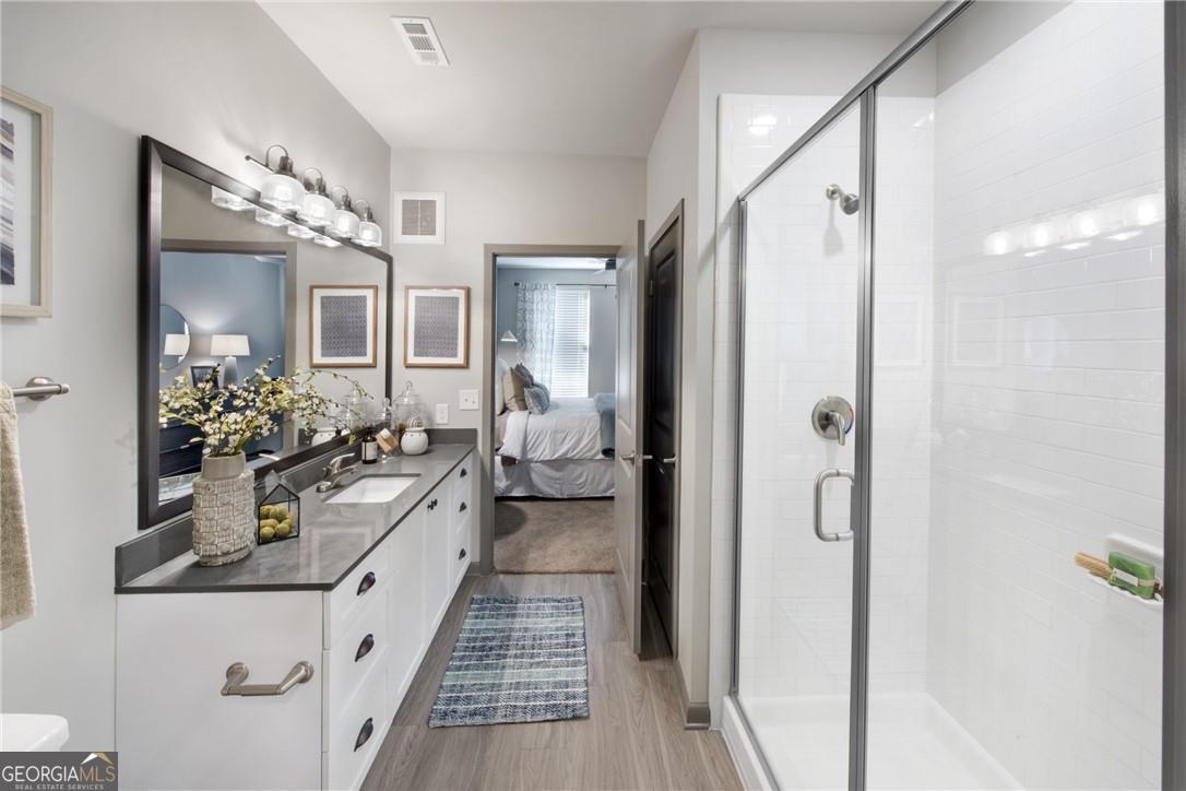6919 Peachtree Road, Unit 545 Atlanta, GA 30328 - Photo 15 of 38 Bathroom featuring an enclosed shower, hardwood / wood-style flooring, and vanity with extensive cabinet space