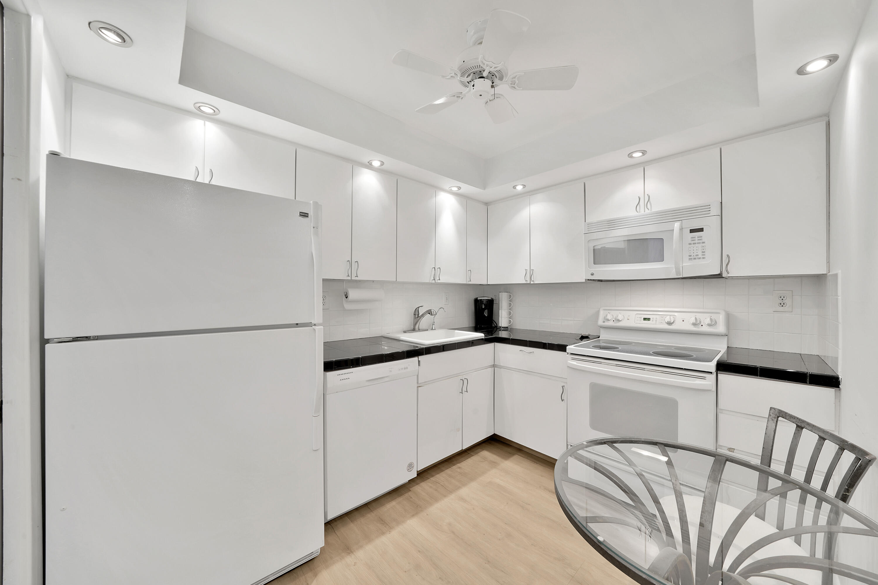 3215 South Ocean Boulevard, Unit 707 Highland Beach, FL 33487 - Photo 11 of 37 a kitchen with stainless steel appliances granite countertop a refrigerator a sink dishwasher a stove and white cabinets with wooden floor