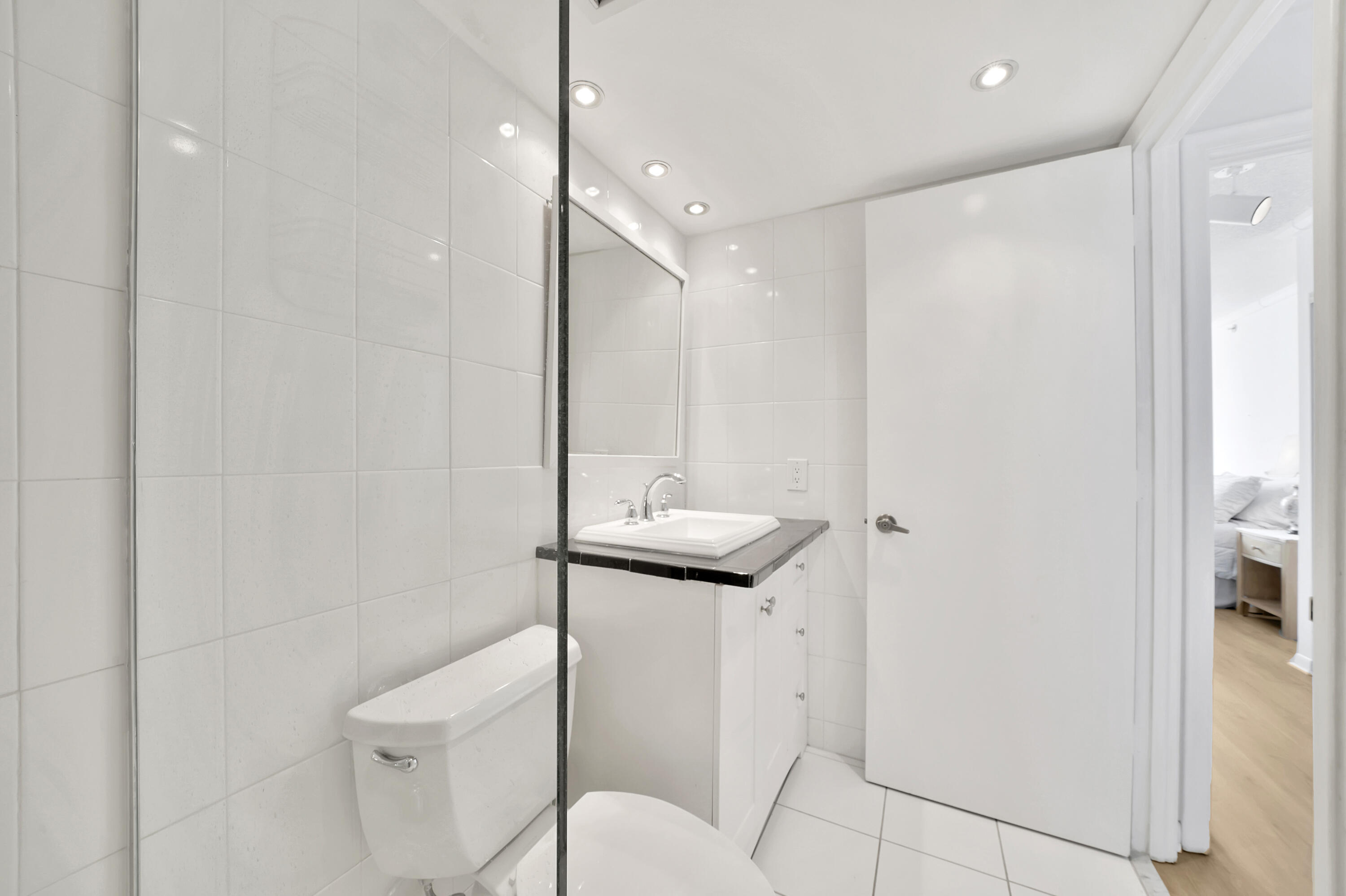 3215 South Ocean Boulevard, Unit 707 Highland Beach, FL 33487 - Photo 20 of 37 a bathroom with a granite countertop sink a toilet a mirror and shower