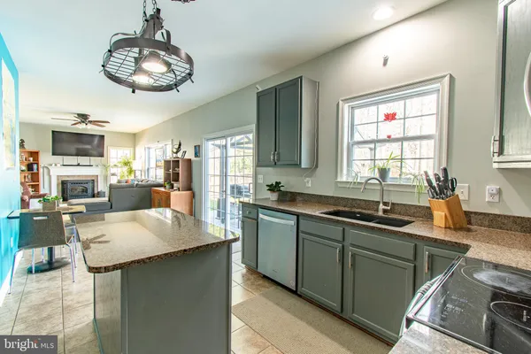 a kitchen with stainless steel appliances granite countertop a sink dishwasher stove refrigerator and couches with wooden floor