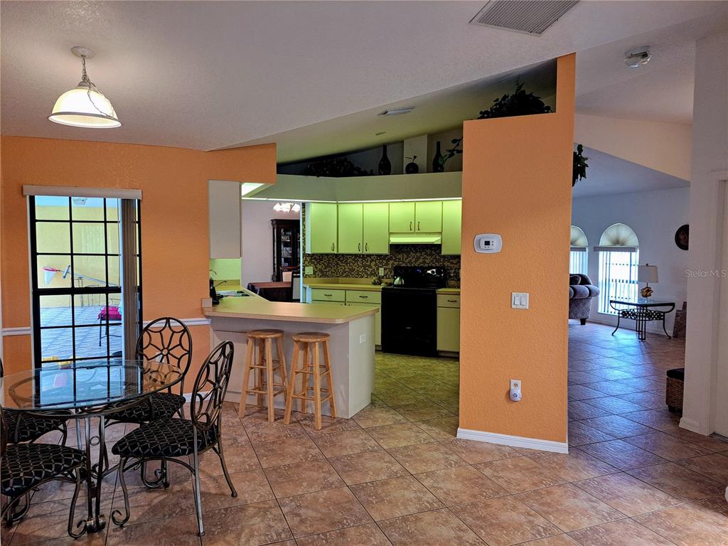 23180 Avacado Avenue Punta Gorda, FL 33980 - Photo 15 of 30 a open kitchen with stainless steel appliances granite countertop a refrigerator a stove top oven a dining table and chairs with wooden floor