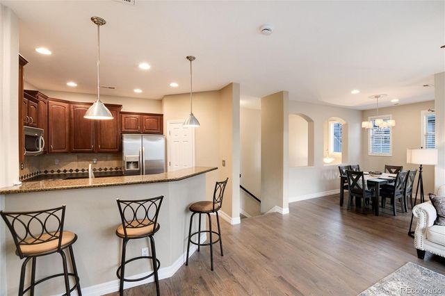 a kitchen with stainless steel appliances kitchen island granite countertop a dining table chairs and white cabinets