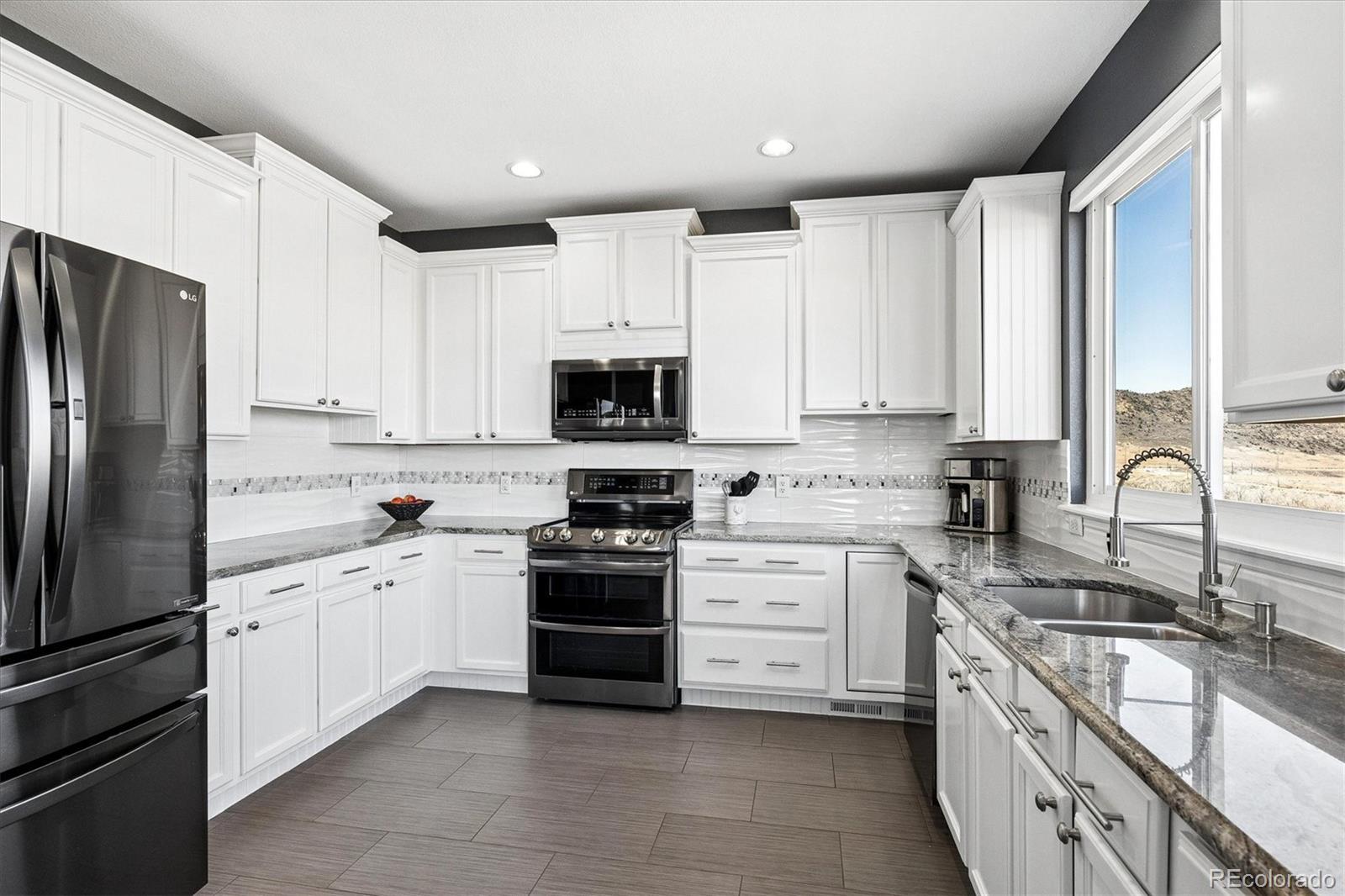 4143 South Deframe Court Morrison, CO 80465 - Photo 22 of 48 a kitchen with white cabinets stainless steel appliances and a sink