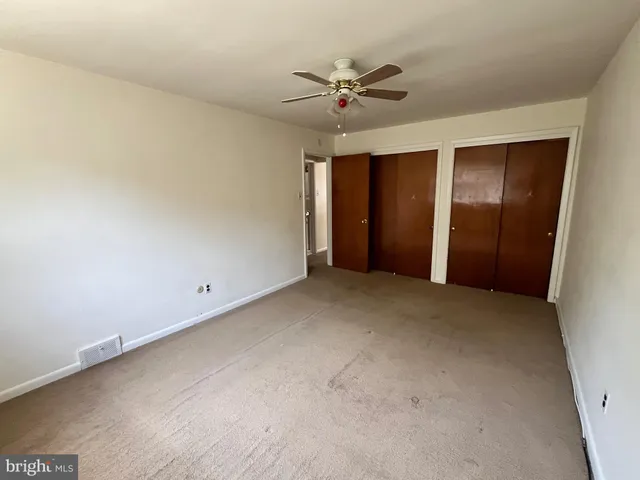 an empty room with chandelier fan and windows