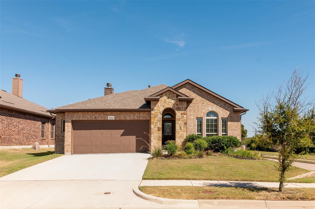 Single story home with a garage, driveway, brick siding, and a front yard
