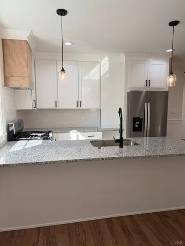 a large kitchen with granite countertop a sink a counter space and cabinets