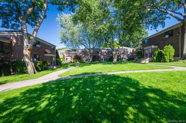 a view of a brick house with a yard and plants