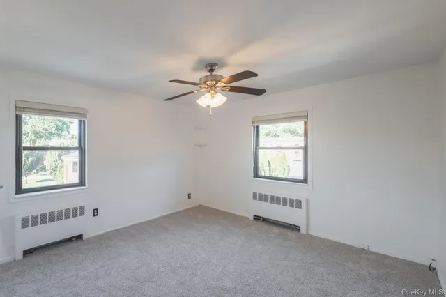 an empty room with chandelier fan and windows