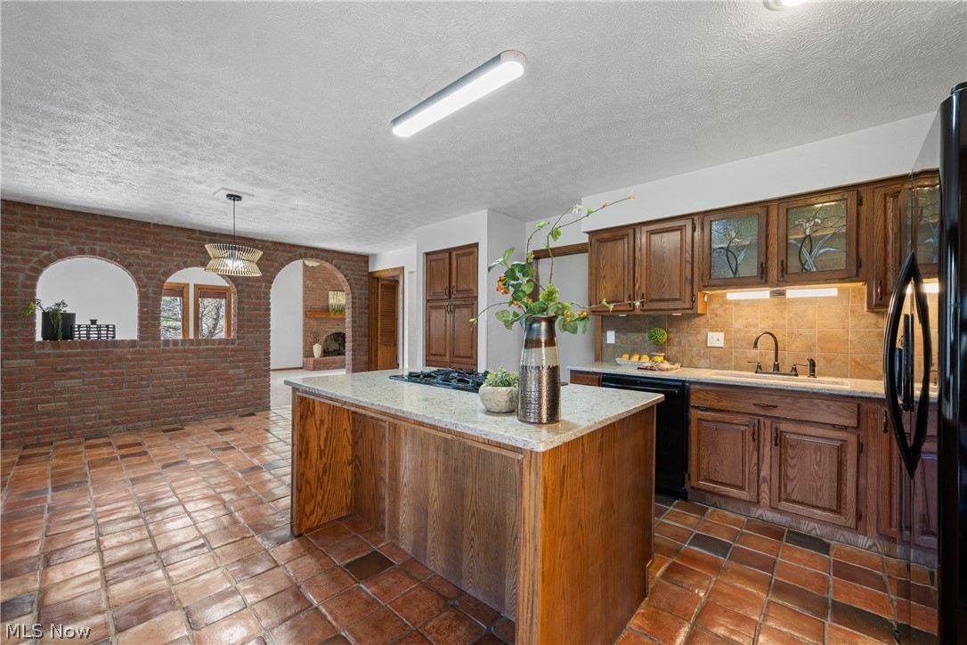Kitchen island with integrated cooktop and counter overhang for barstool seating.