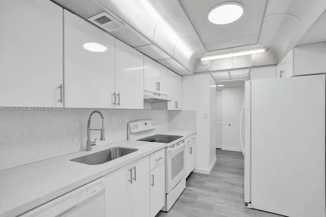 a kitchen that has a lot of white cabinets and wooden floor