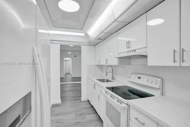 a kitchen with white cabinets appliances and sink