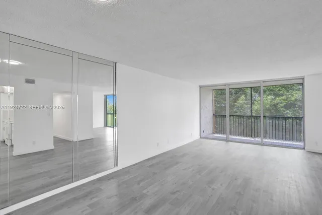 a view of a big room with wooden floor and windows