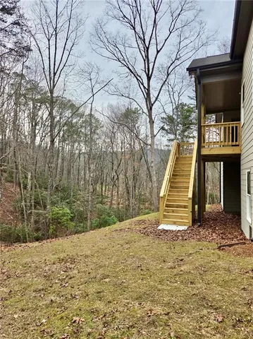a view of wooden house and a yard with trees