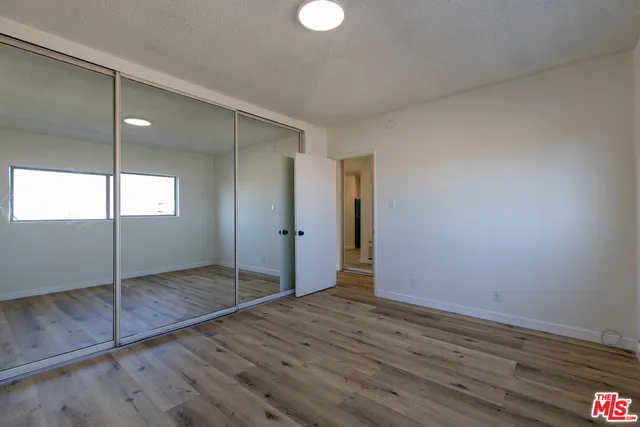 an empty room with wooden floor mirror and windows