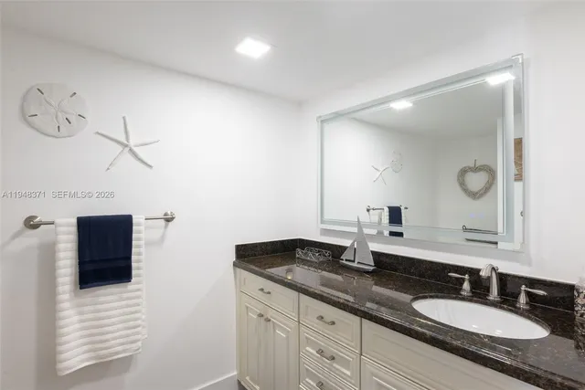 a bathroom with a granite countertop double vanity sink and mirror
