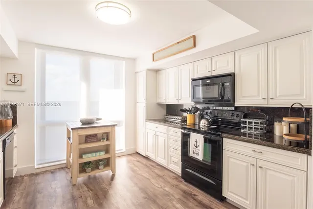 a kitchen with granite countertop a stove a sink and a microwave