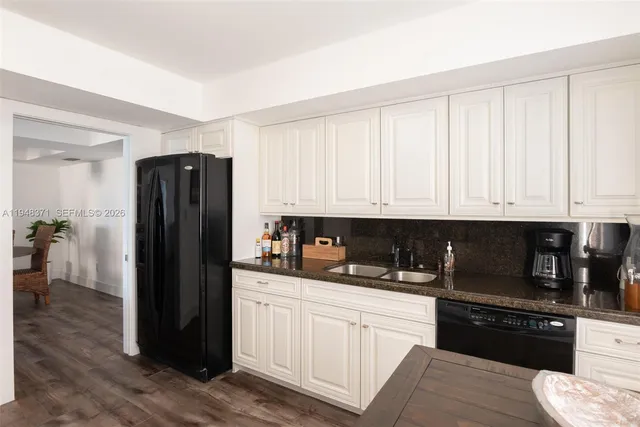a kitchen with granite countertop white cabinets and refrigerator