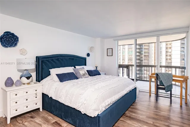 a bedroom with a bed a large window and walk in closet with wooden floor