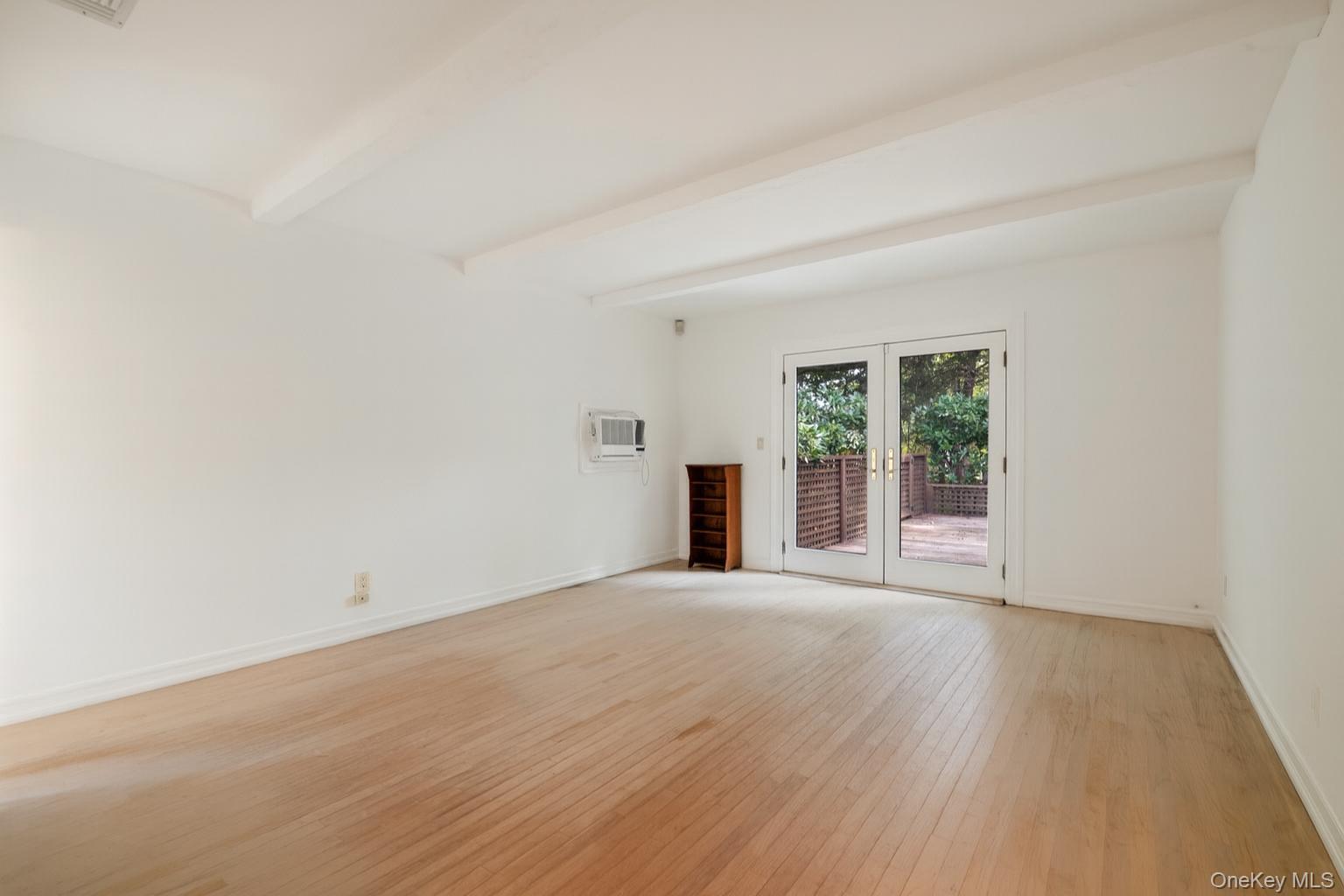 40 Nidzyn Avenue Remsenburg, NY 11960 - Photo 14 of 28 Empty room featuring light wood-style flooring, beamed ceiling, french doors, and a wall unit AC