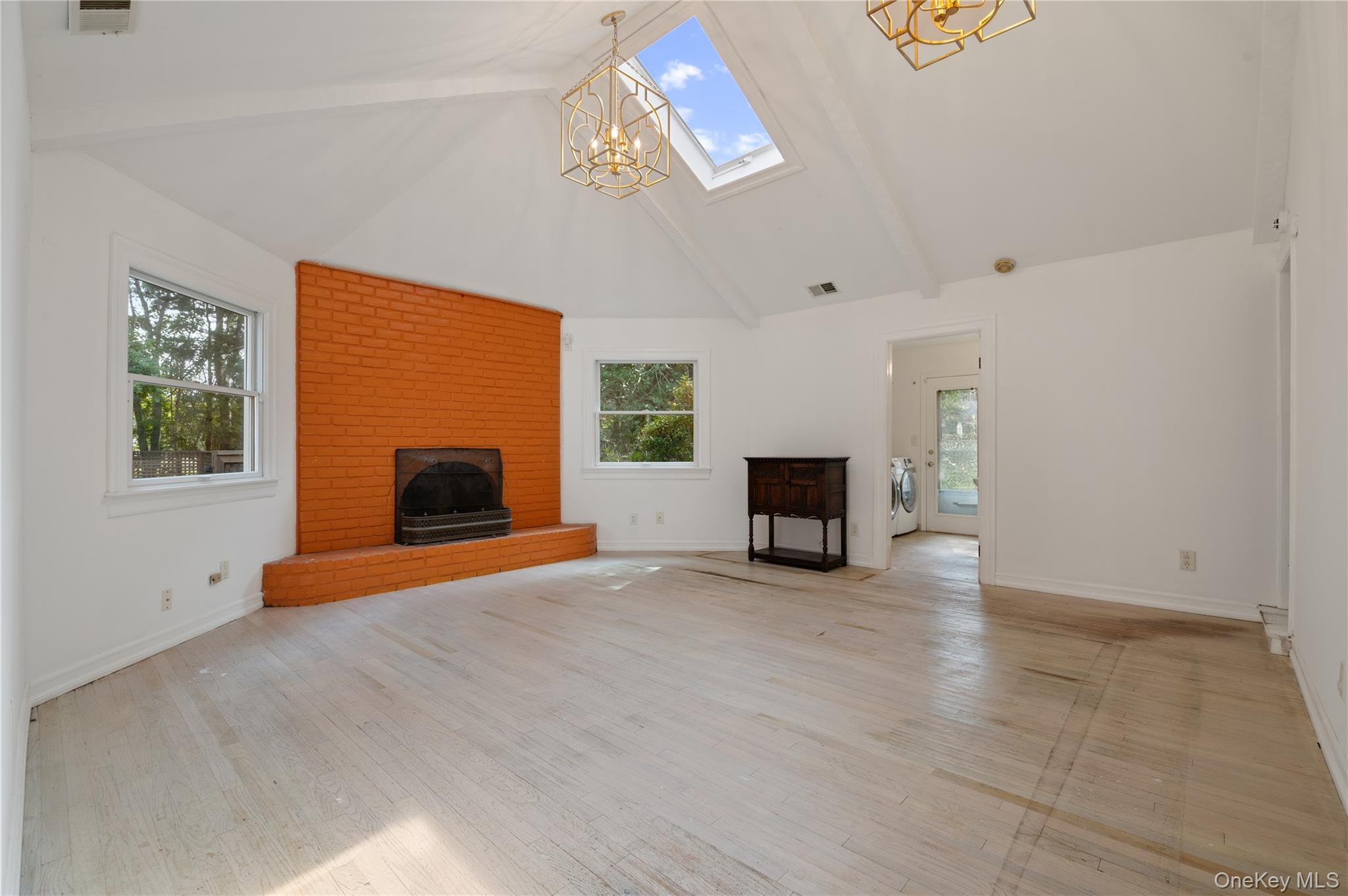 40 Nidzyn Avenue Remsenburg, NY 11960 - Photo 9 of 28 Unfurnished living room with high vaulted ceiling, plenty of natural light, beamed ceiling, a chandelier, and light wood-type flooring