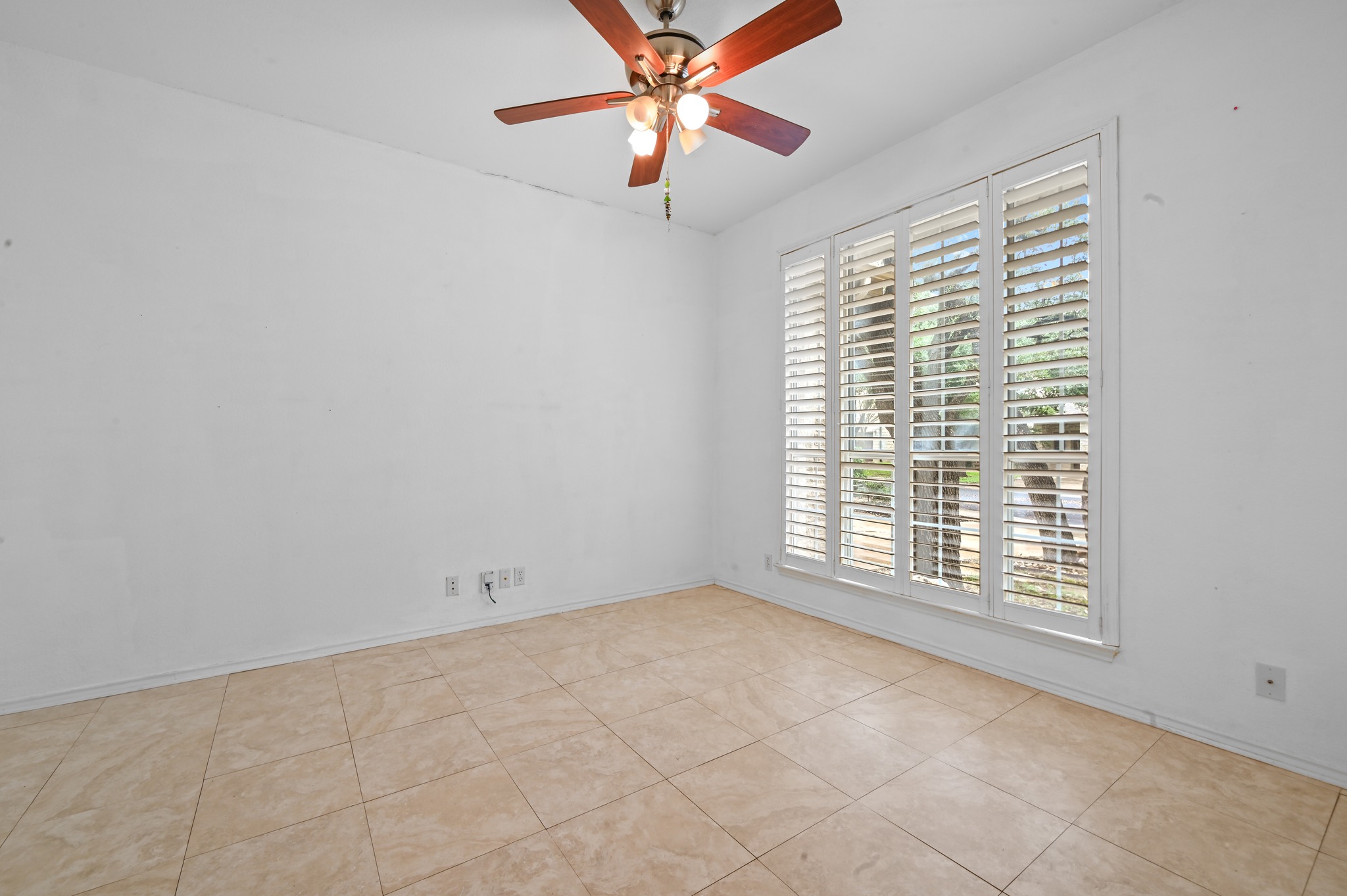 5313 Moon Shadow Drive Austin, TX 78735 - Photo 7 of 30 Spacious room featuring a large window with white plantation shutters, neutral tile flooring, and a ceiling fan with integrated lighting