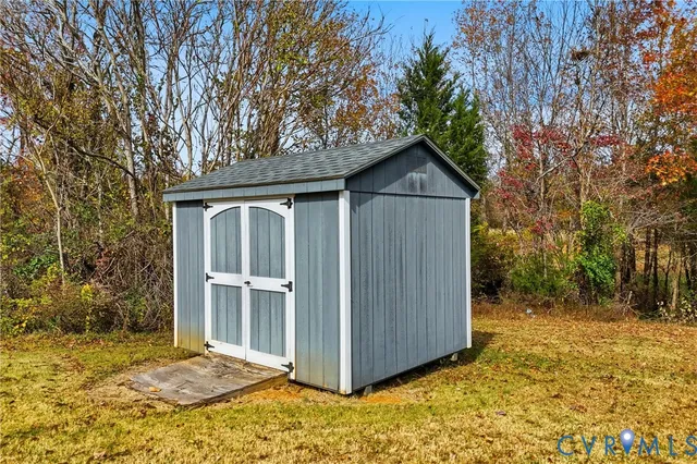 a view of wooden house with a yard and large tree