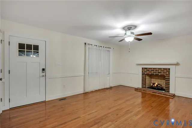 an empty room with wooden floor chandelier fan and windows