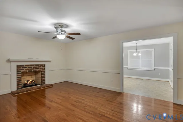an empty room with wooden floor chandelier fan and windows