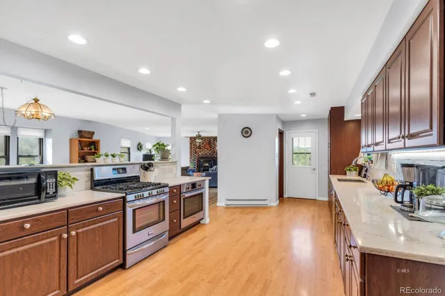 a large kitchen with stainless steel appliances granite countertop a lot of counter space and wooden floor