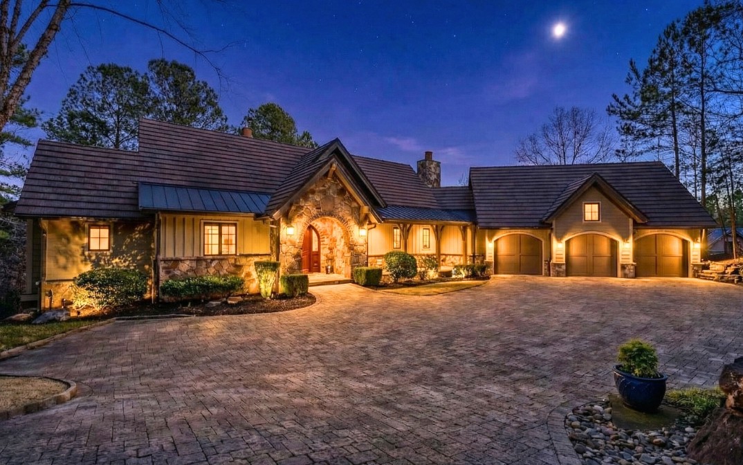 This charming home features a stone and wood exterior, multiple garages, and a paver driveway.