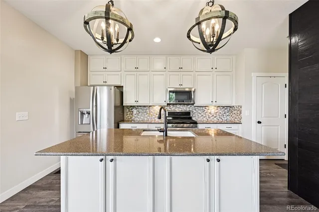 a kitchen with stainless steel appliances granite countertop a sink a stove and a refrigerator