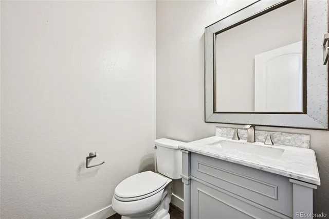 a bathroom with a granite countertop toilet sink and mirror