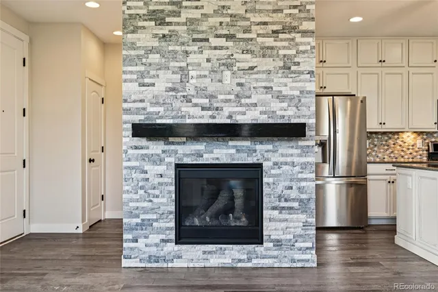a living room with stainless steel appliances wooden floor and a fireplace