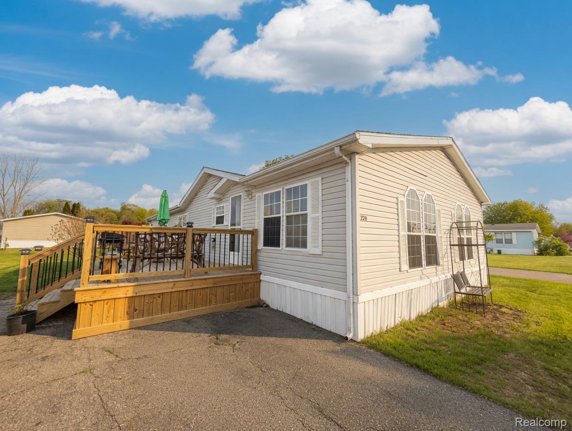6988 McKean Road Ypsilanti, MI 48197 - Photo 26 of 31 View of property exterior featuring a deck and a lawn