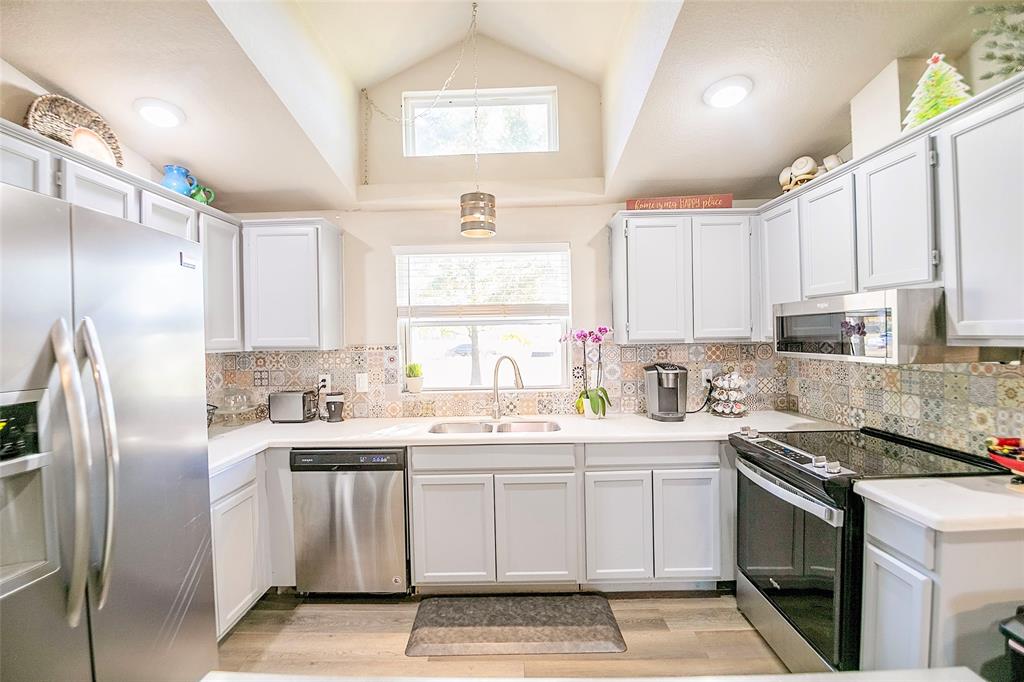 11661 Dane Road Pilot Point, TX 76258 - Photo 11 of 40 a kitchen with a sink stove a refrigerator and white cabinets