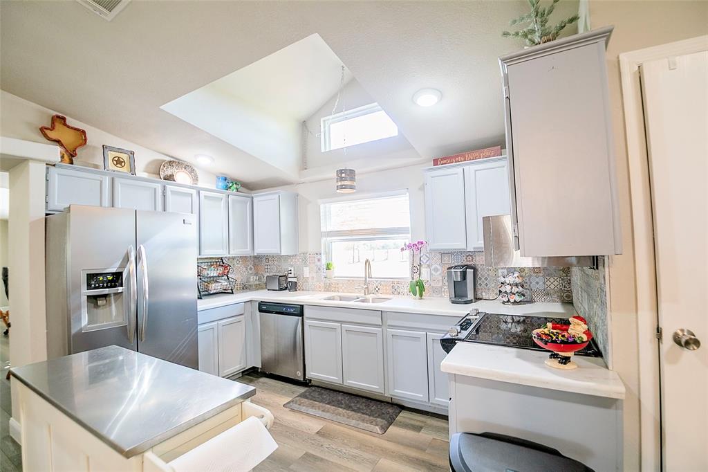 11661 Dane Road Pilot Point, TX 76258 - Photo 12 of 40 a kitchen with white cabinets and stainless steel appliances
