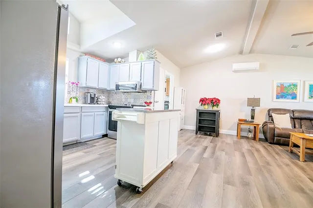 a kitchen with kitchen island a stove a sink dishwasher and white cabinets with wooden floor