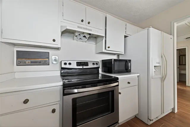 a kitchen with cabinets stainless steel appliances and wooden floor