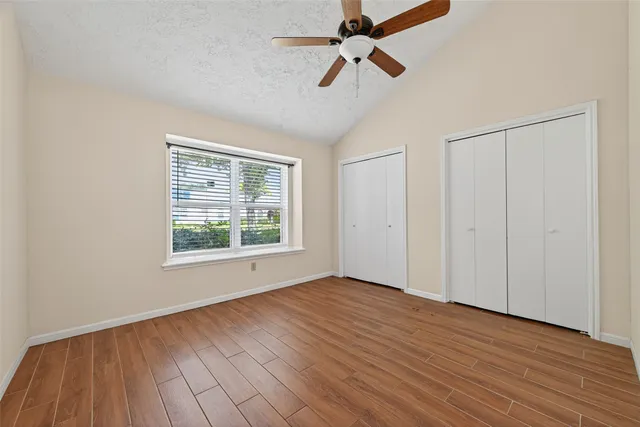 a view of empty room with wooden floor and fan