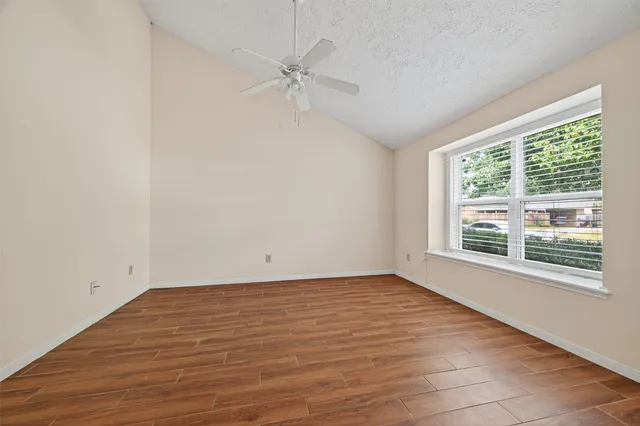 a view of an empty room with a window and wooden floor