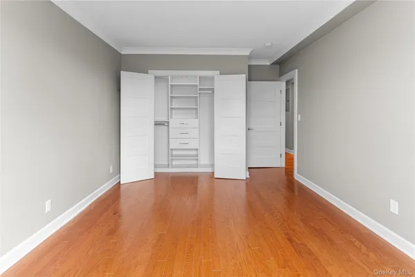 a view of an empty room with wooden floor and closet