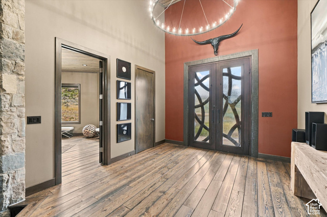 5936 Triple Crown Trail Oakley, UT 84055 - Photo 5 of 57 Wood-finish flooring throughout, double entry doors with decorative ironwork, stone accent wall, high ceilings, and a circular chandelier