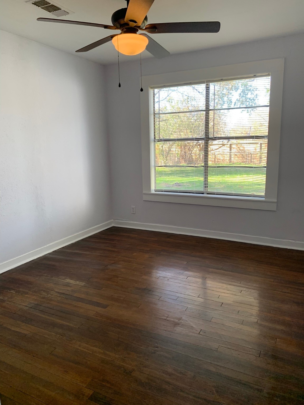 1315 Penick Road Waller, TX 77484 - Photo 9 of 13 an empty room with wooden floor chandelier fan and windows