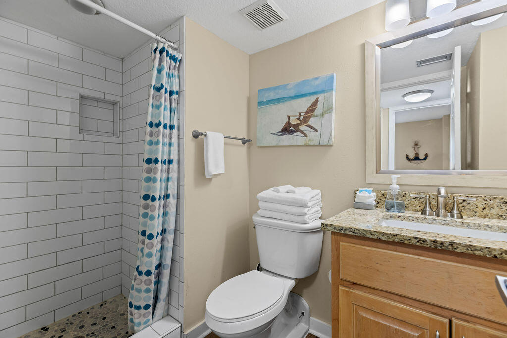 909 Santa Rosa Boulevard, Unit 569 Fort Walton Beach, FL 32548 - Photo 30 of 57 a bathroom with a granite countertop toilet a sink a mirror and shower curtain